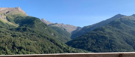 A mountain landscape with a wooden railing in the foreground.