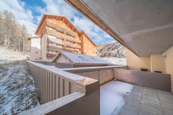 A modern building with a balcony and a view of a mountainous landscape.