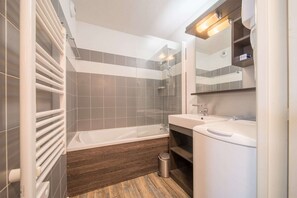 A modern bathroom with a bathtub, a shower, and a sink.