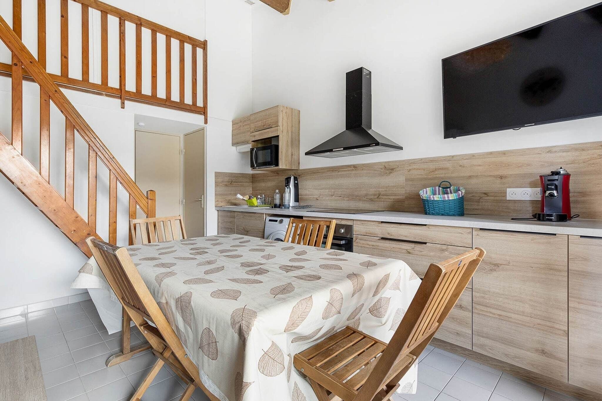 Une cuisine avec des meubles en bois, un four à micro-ondes, une cuisinière et un téléviseur fixé au mur.