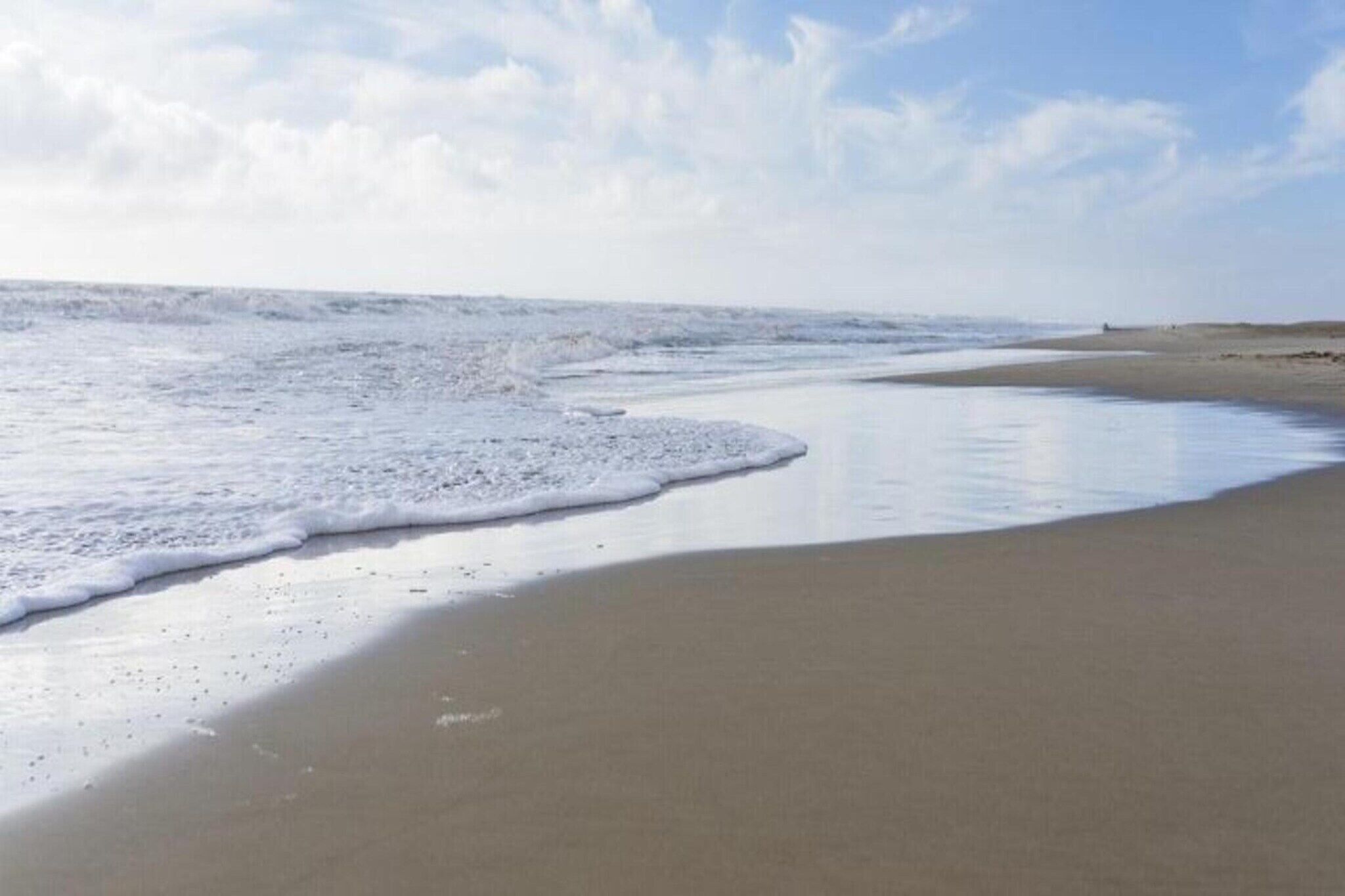Une plage au sable humide et aux vagues douces.