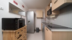 A compact kitchen with a microwave, refrigerator, dishwasher, and wooden cabinets.