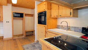 A compact kitchen with wooden cabinets, a built-in microwave, a stove, and a sink.