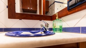 Un lavabo de salle de bain avec un receveur bleu, un robinet chromé et un distributeur de savon vert.
