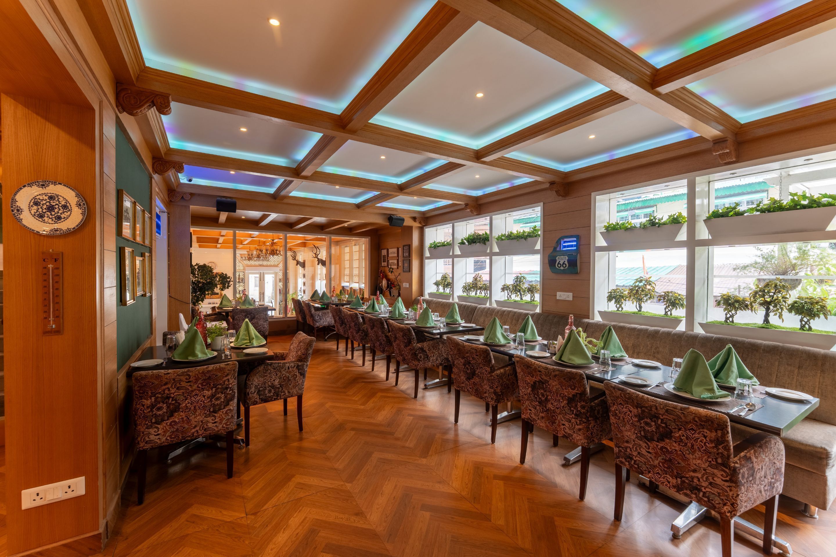 A restaurant with wooden beams and a herringbone floor. Tables are set with green napkins and plates.