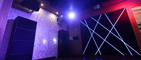 A room with a patterned wall, a speaker, and a geometric light display.