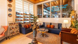 A cozy living room with two sofas, a coffee table, and a bookshelf filled with books. - Moustache Mussoorie (Uttarakhand)