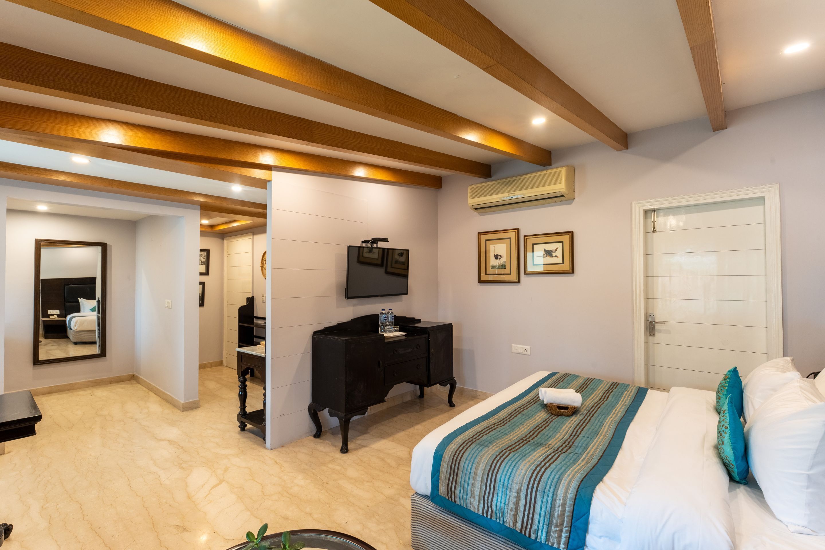 Un dormitorio con cama, televisor, cómoda y puerta.