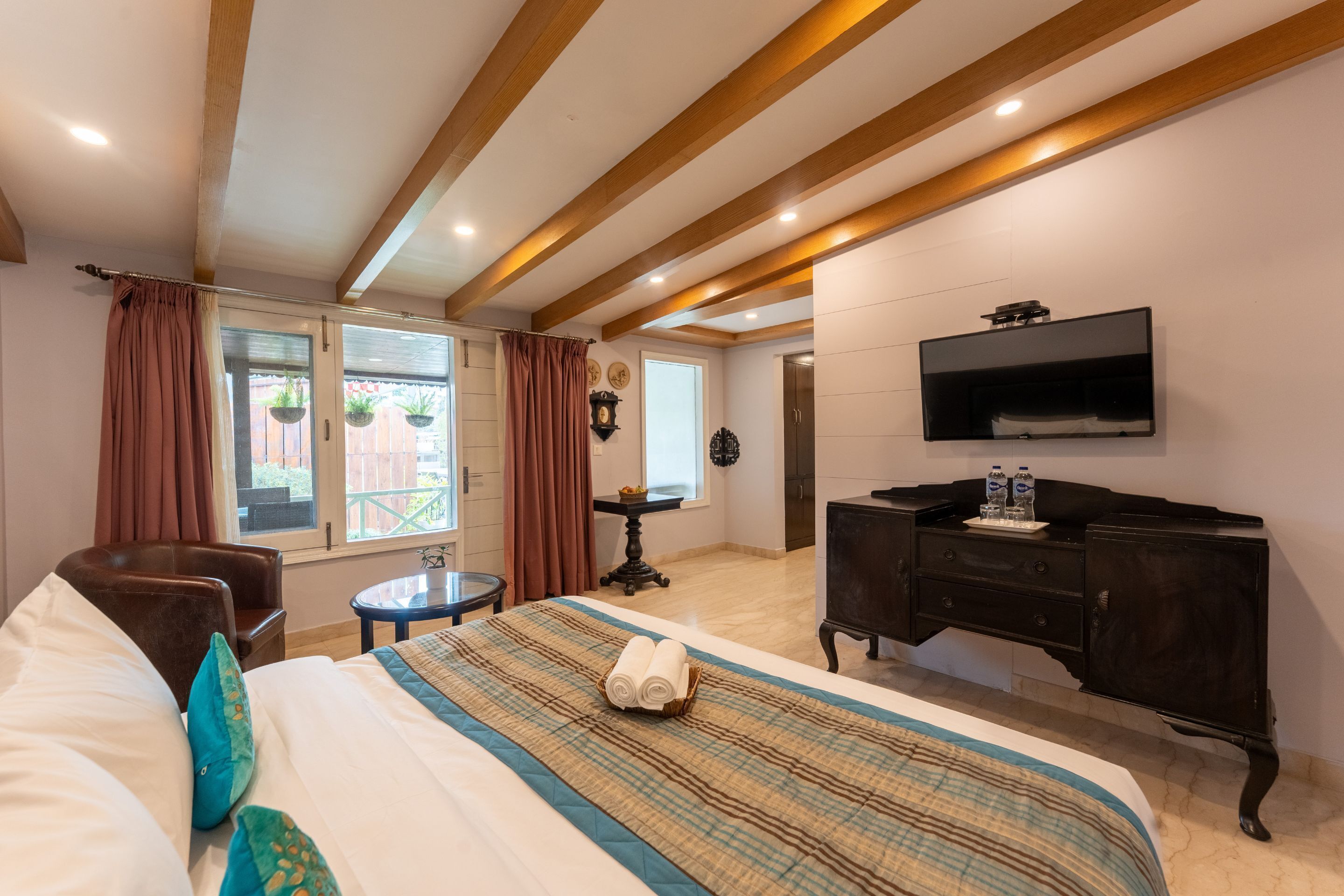 Ein Hotelzimmer mit Bett, Schreibtisch, Stuhl, Fernseher und einem Fenster mit Vorhängen.