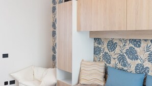 A bedroom with a bunk bed, a chair, and patterned wallpaper. - Exclusive Guest House - Fiera Milano Rho (Rho)