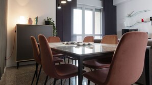 A modern dining area with a glass-top table, six chairs, and pendant lighting. - Exclusive Guest House - Fiera Milano Rho (Rho)