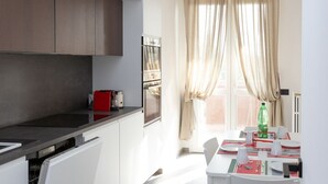 A modern kitchen with a built-in oven and a dining area with a table set for two. - Exclusive Guest House - Fiera Milano Rho (Rho)