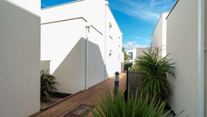 A narrow pathway leading to a building with white walls and a wooden deck. - Cozy Villa Steps from the Beach (Valras-Plage)