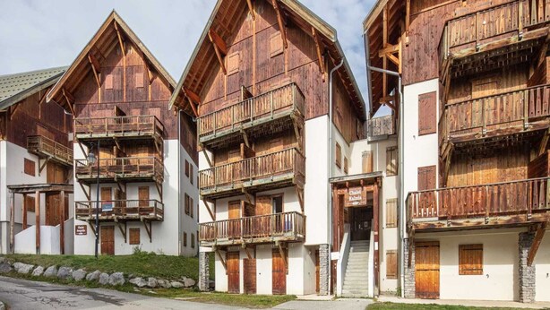 Una hilera de edificios tradicionales de madera con balcones, probablemente parte de un complejo turístico en la montaña.