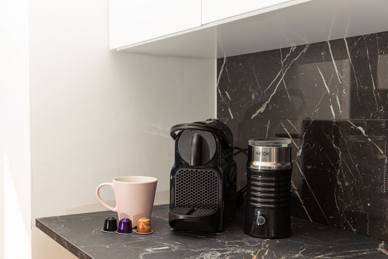 Un piano di lavoro in cucina con una macchina da caffè, un thermos e una tazza.