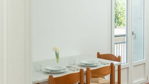 Ein Esstisch mit weißen Tellern, eine Vase mit einer einzelnen Blume und ein Fenster mit Blick ins Grüne.