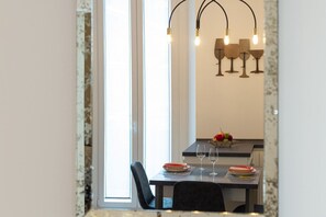 A dining area with a table set for two, a fruit bowl, and a wine glass. - Navigli - Design Exclusive Apartment (Milano)