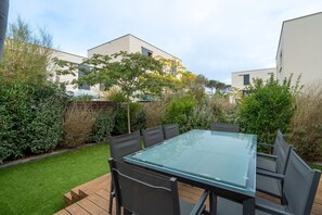 Ein Esstisch mit Glasplatte und sechs Stühlen in einem Garten.