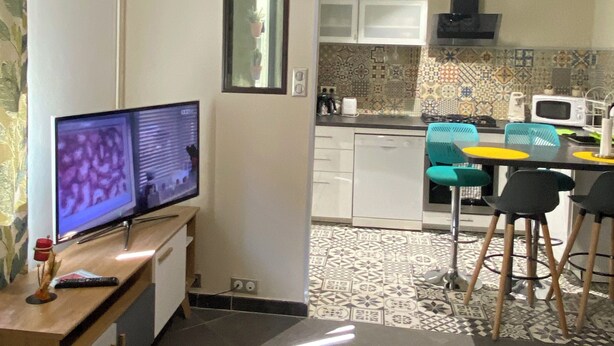A compact living space with a TV, a small kitchen with a microwave, and a dining area with chairs. - Zahra D'or (Plombières-lès-Dijon)