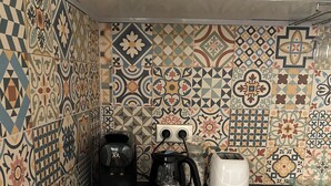 A kitchen with patterned tiles, a black coffee maker, a white electric kettle, and a white appliance on the counter. - Zahra D'or (Plombières-lès-Dijon)