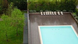 Una piscina en la azotea con sillas de descanso y un jardín que la rodea.