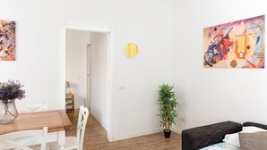 A modern living space with a wooden dining table, white chairs, a black sofa, and a potted plant. - Kandinsky - Exclusive Apartment (Milano)