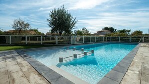 Una piscina rectangular amb aigua cristal·lina blava, envoltada per una tanca blanca i un pont de fusta.