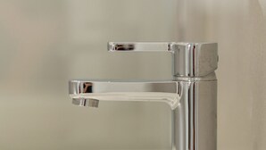 A chrome faucet with a single handle and a side lever, mounted on a white sink. - Klimt Central station - Two Room Apartment (Milano)