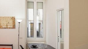 A dining area with a table set for two, a floor lamp, and a window with blinds. - Klimt Central station - Two Room Apartment (Milano)