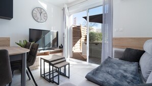 A modern living room with a flat-screen TV, a wooden dining table, and a sofa. - Bright Retreat Near Beach (Sérignan)