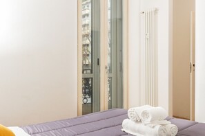A hotel room with a bed, a radiator, and a view of a balcony with a railing. - FREE PARKING Exclusive apartment Magritte Style (Milano)