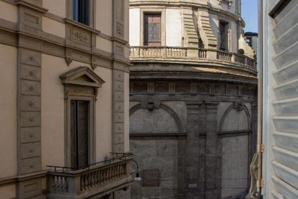 A historic building with a classical facade, a balcony, and a large arched entrance.
