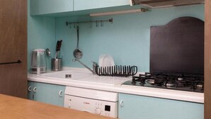 A kitchen with a Bosch dishwasher, a stove, and a hanging rack with utensils. - Mint - Van Gogh - Dome Cathedral (Milano)