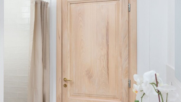 A wooden door with a brass handle and a lock, a beige curtain, and a white orchid plant. - New Exclusive Melegnano Apartments- Near train station X4 (Melegnano)