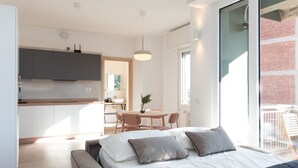 A modern bedroom with a large bed, a small desk, and a dining area.