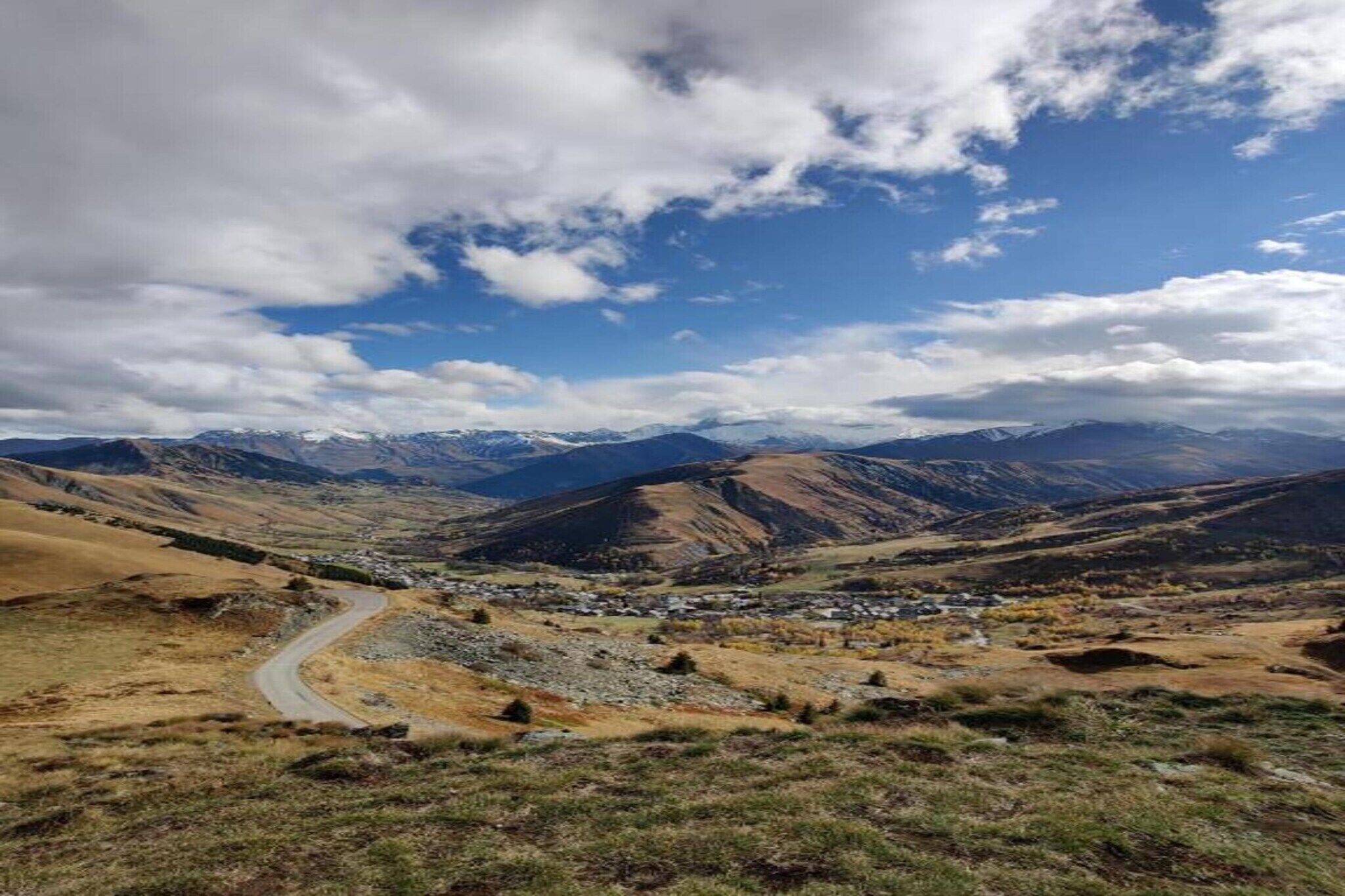 A mountainous landscape with a winding road and a small settlement.