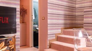 A modern living room with a large flat-screen TV, a staircase, and a patterned wallpaper. - Piazza del Carmine - Gold Exclusive Apartment - APARTMENT IN THE UNDERGROUND (Milano)