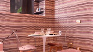 A dining area with a zigzag patterned wall, a round table set with plates, glasses, and cutlery, and two chairs with transparent backs. - Piazza del Carmine - Gold Exclusive Apartment - APARTMENT IN THE UNDERGROUND (Milano)