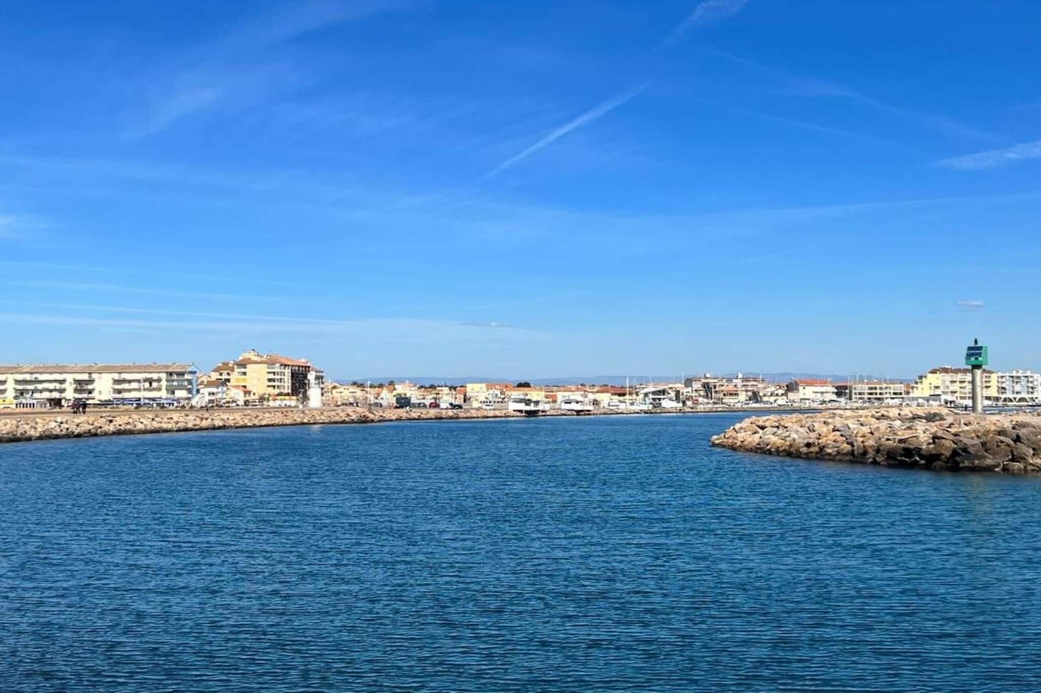 A coastal town with a marina, buildings along the waterfront, and a clear blue sky.