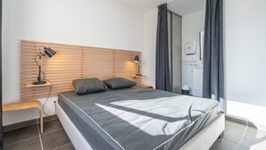 Un dormitorio moderno con una cama grande, cabecera de madera, lámparas de noche y un banco.