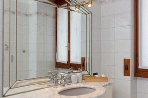 A bathroom with a large mirror, a sink, and a wooden vanity. - Spacious Exclusive Apartment (Pioltello)
