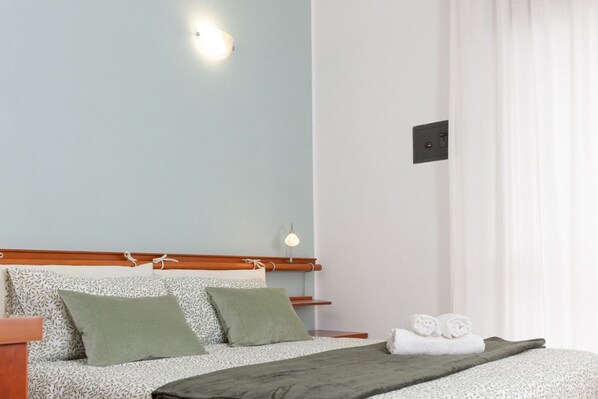 A neatly arranged bedroom with a bed, pillows, a bedside table, and a lamp. - Spacious Exclusive Apartment (Pioltello)