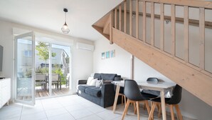 A modern living room with a sofa, dining table, chairs, and a staircase. - Charming Villa in Valras-Plage (Valras-Plage)