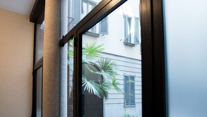 Une fenêtre donnant sur un bâtiment avec des volets et un palmier.