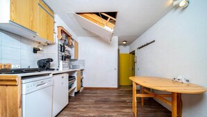 A compact kitchen with white appliances, wooden cabinets, and a wooden dining table. - Apartment in French Alps near Ski Resort (Allos)