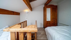 A small, cozy room with a wooden bunk bed, a wooden desk, a wardrobe, and a skylight. - Apartment in French Alps near Ski Resort (Allos)