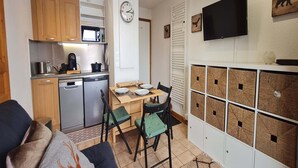 Una cocina compacta con comedor, un reloj y armarios de almacenamiento.