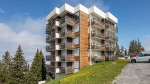 A multi-story residential building with balconies, set against a backdrop of trees and a clear sky. - Alpine Escape at Chamrousse (Chamrousse)