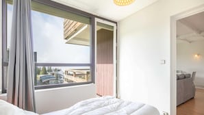 A modern bedroom with a large window, a bed with white bedding, and a view of the outside balcony. - Alpine Escape at Chamrousse (Chamrousse)