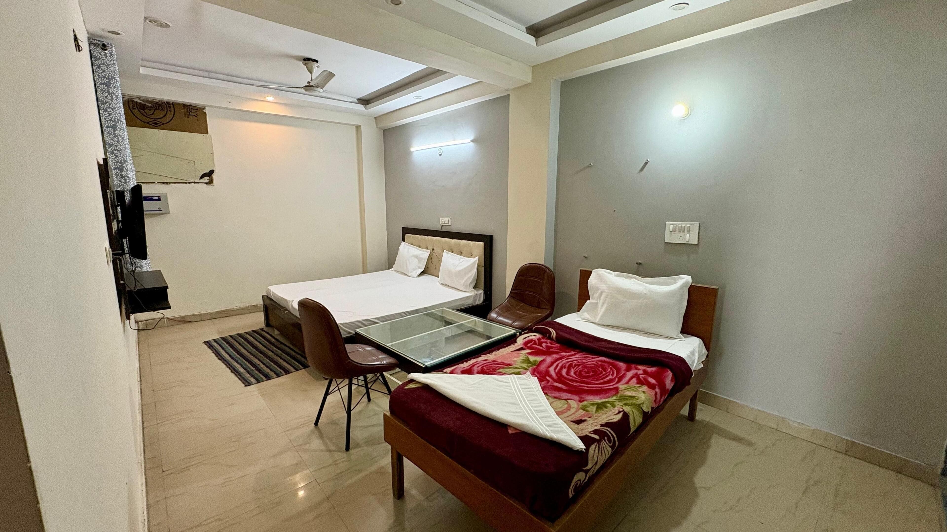 A hotel room with a bed, a desk, and a chair. There is a ceiling fan and a light fixture.